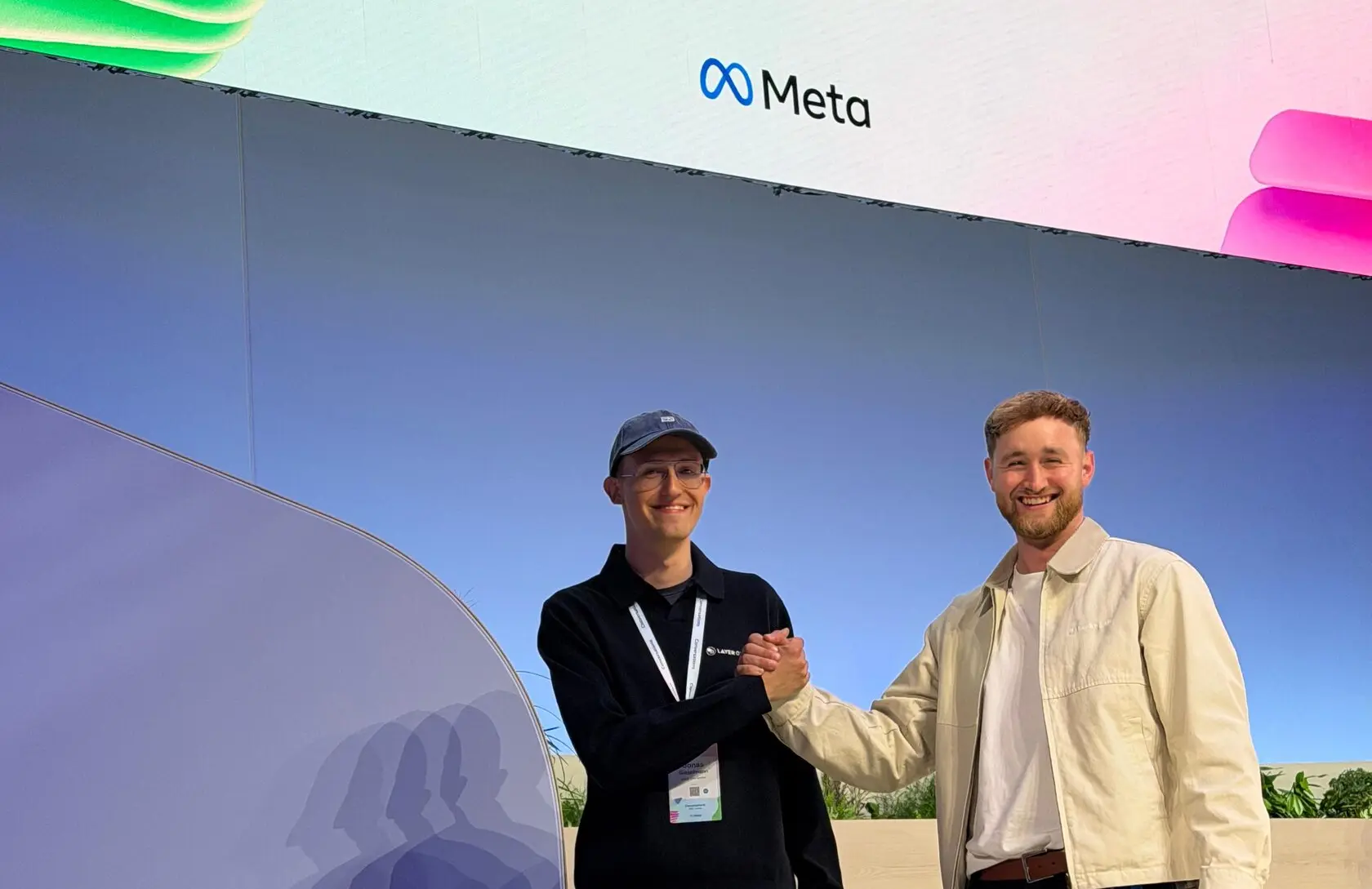Two of the team in front of a Meta stage wall
